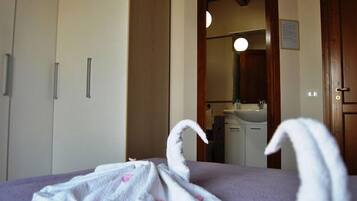Comfortable retreat with a bed, wardrobe, and en-suite bathroom featuring a sink and mirror.