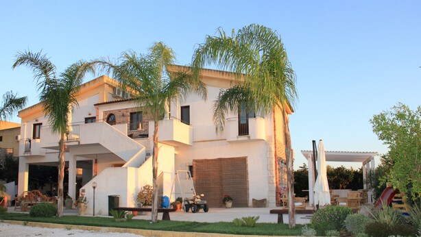 A modern two-story house with a flat roof, a covered patio, and a driveway. - I Giardini di Elencosta (Misiliscemi)