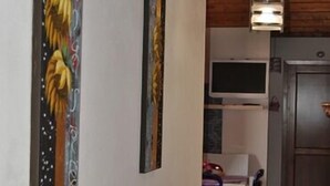 A modern kitchen with a built-in microwave, a refrigerator, and a dining area with white chairs. - I Giardini di Elencosta (Misiliscemi)