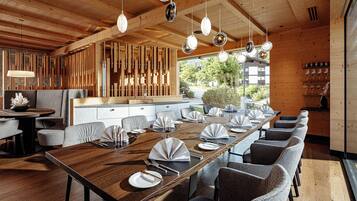 Un comedor moderno con una larga mesa de madera, sillas tapizadas en gris y lámparas colgantes.