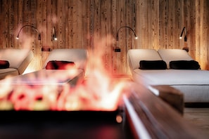 Una habitación con pared de madera, dos camas y una chimenea.