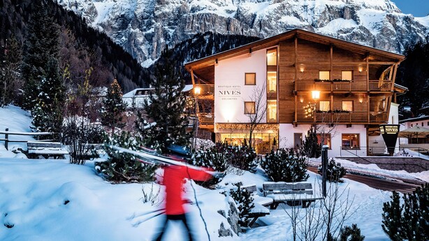 Un hotel con fachada de madera, balcones y un letrero que dice "NIVES Boutique Hotel".