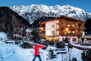 A hotel with a wooden facade, balconies, and a sign reading "NIVES Boutique Hotel." - Boutique Hotel Nives (Selva di Val Gardena)