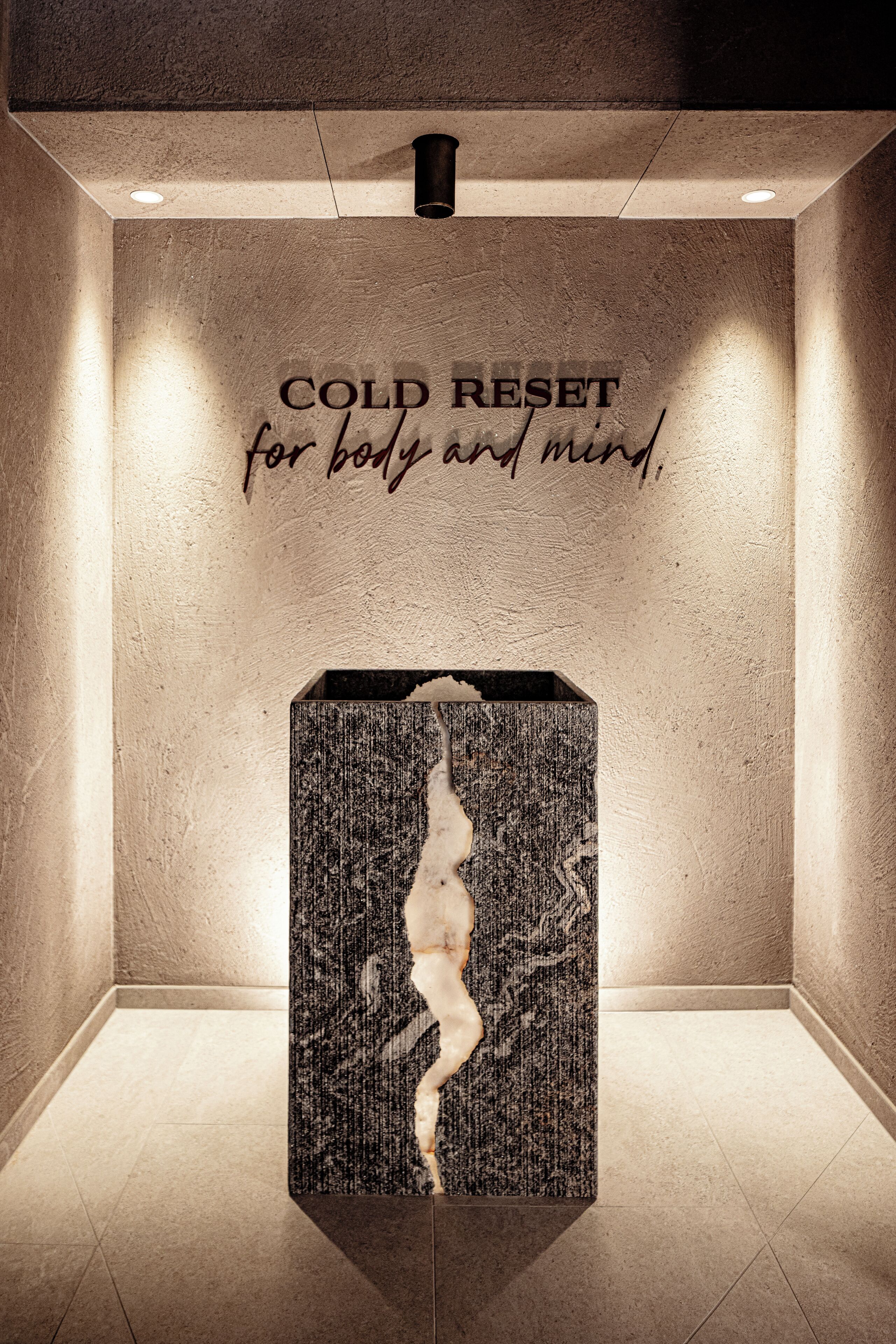 Eine Wand mit dem Schriftzug 'COLD RESET für Körper und Geist' und einem reliefartigen Panel mit einer Silhouette.