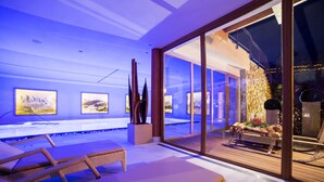 Un área de spa moderna con sillones reclinables, una terraza de madera y vistas a la piscina.