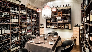 Una bodega con estantes llenos de botellas de vino, una mesa de comedor para cuatro personas y una araña.