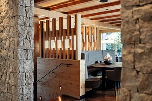 Un interior de madera con pared de piedra, una partición de madera y una zona de comedor con sillas y una mesa.