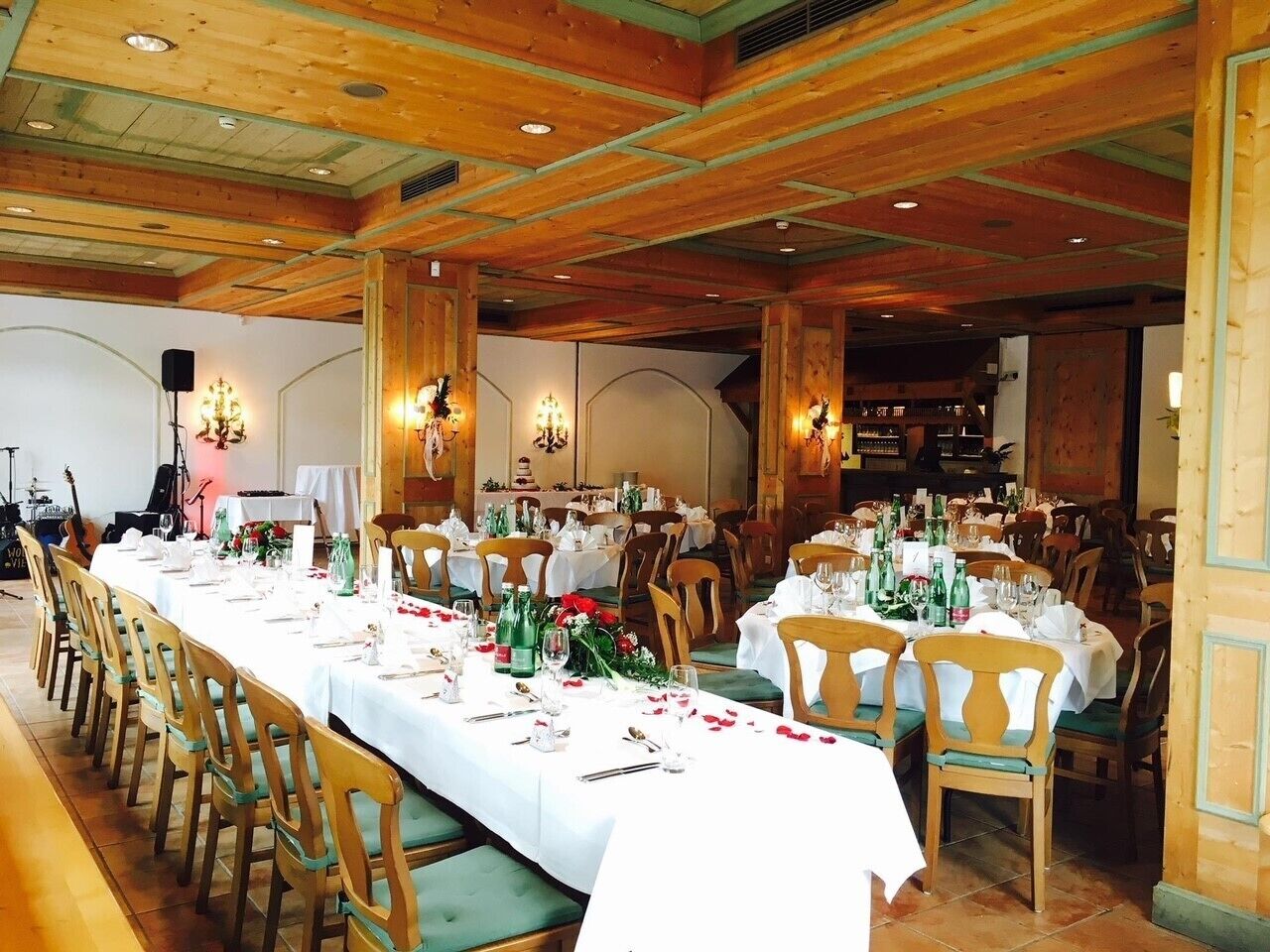 Una larga mesa de comedor dispuesta con sillas, manteles blancos y centros de mesa florales.