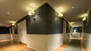 Un couloir doté d’un plancher en bois, de lambris blancs, de panneaux muraux sombres et d’appliques murales.