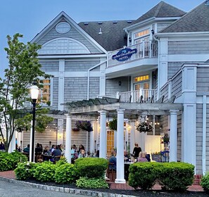 A hotel with a covered outdoor seating area, multiple dining tables, and a sign indicating it is a hotel.