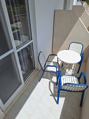 A small outdoor seating area with a table and chairs, a sliding glass door, and a tiled floor.