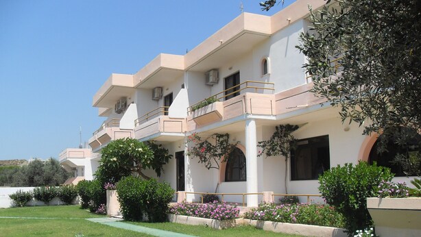 A multi-story hotel with balconies, a green lawn, and various plants. - Vera Studios (Rhodes)