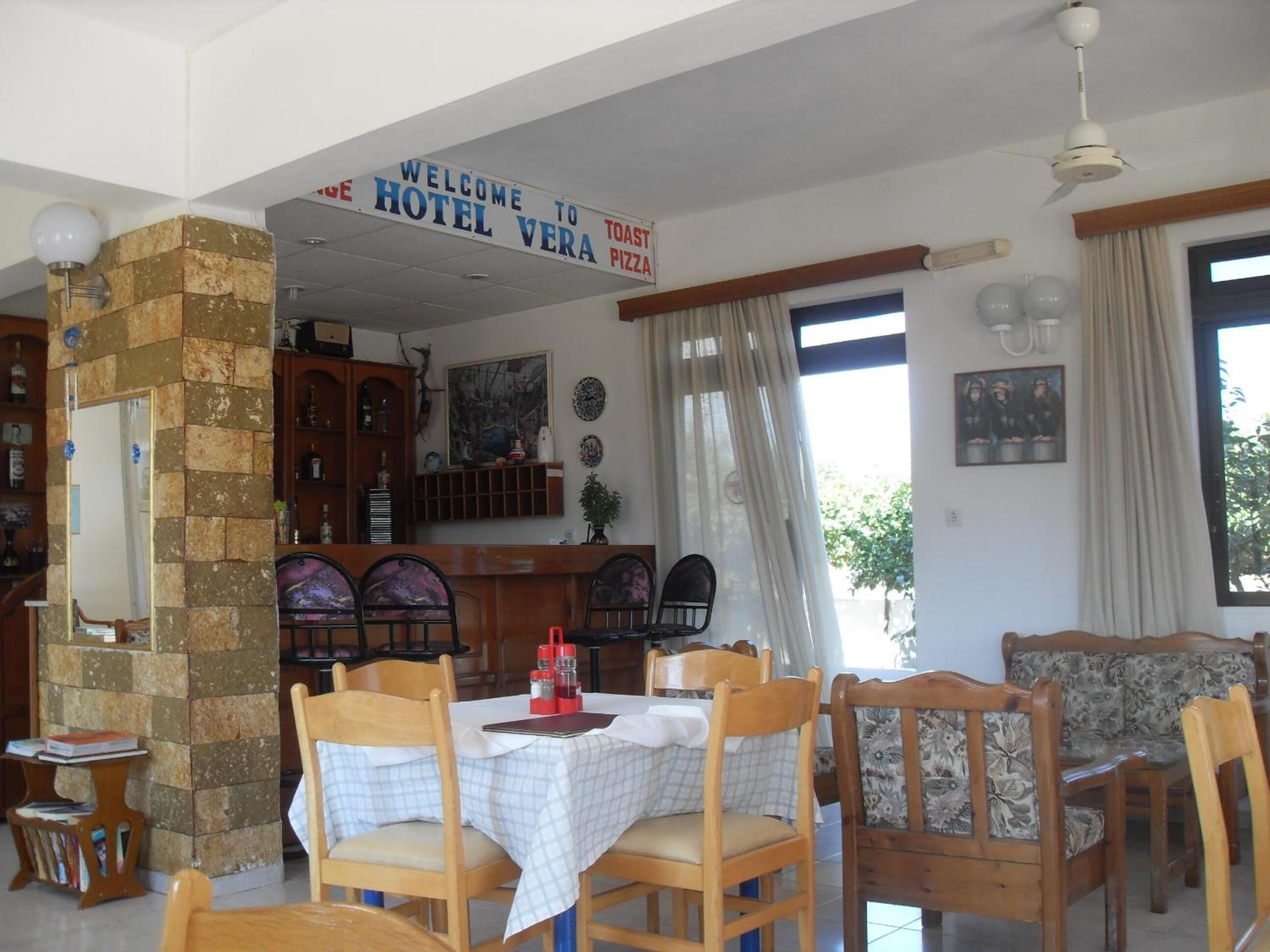 A dining area with a sign reading "WELCOME TO HOTEL VERA TOAST PIZZA".