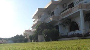 A multi-story building with balconies and a grassy lawn in the foreground. - Vera Studios (Rhodes)