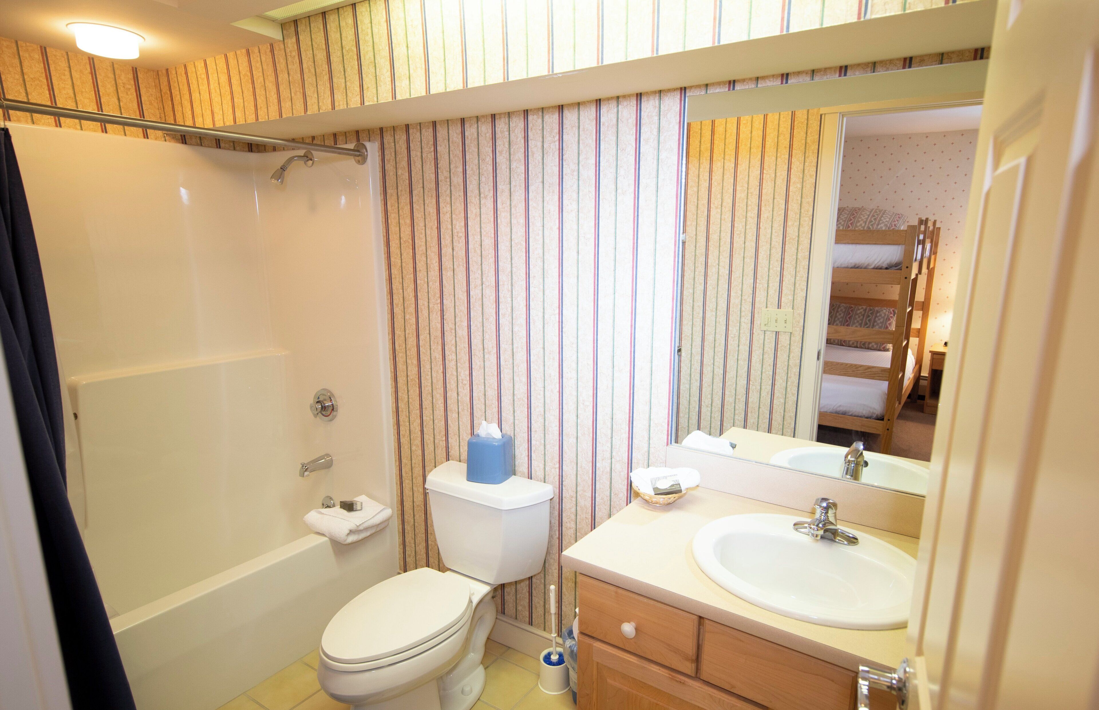 A bathroom with a bathtub, toilet, sink, and a mirror.