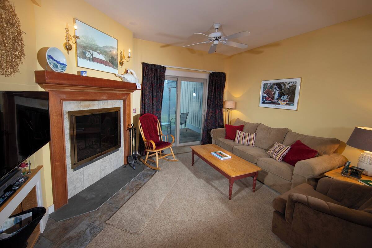 A living room with a fireplace, a sofa, a rocking chair, and a television.