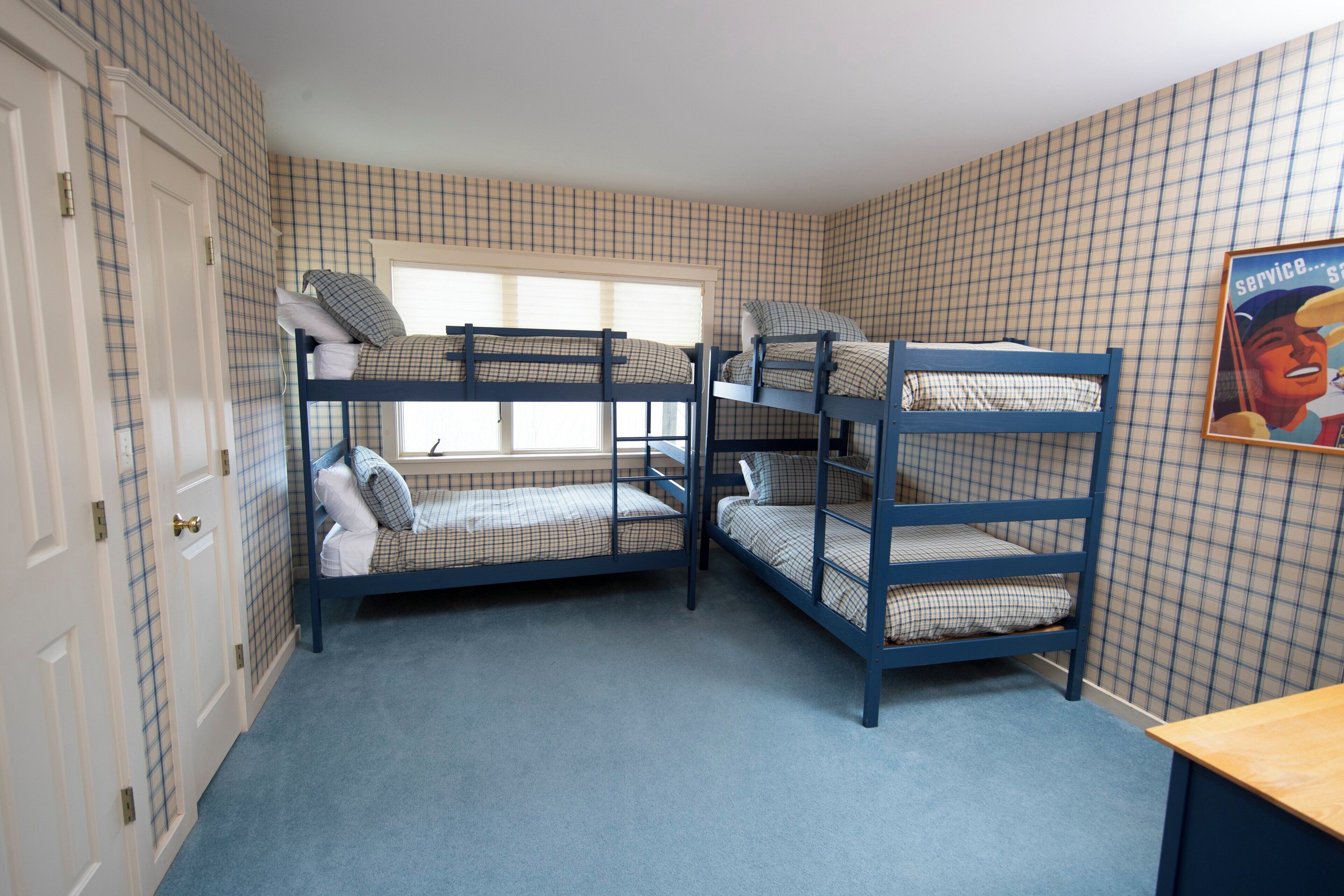 A room with bunk beds, a window, and a poster on the wall.