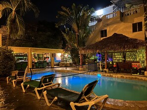 A pool area with lounge chairs, a bar, and a thatched-roof structure. - Coco Hotel (Sosúa)