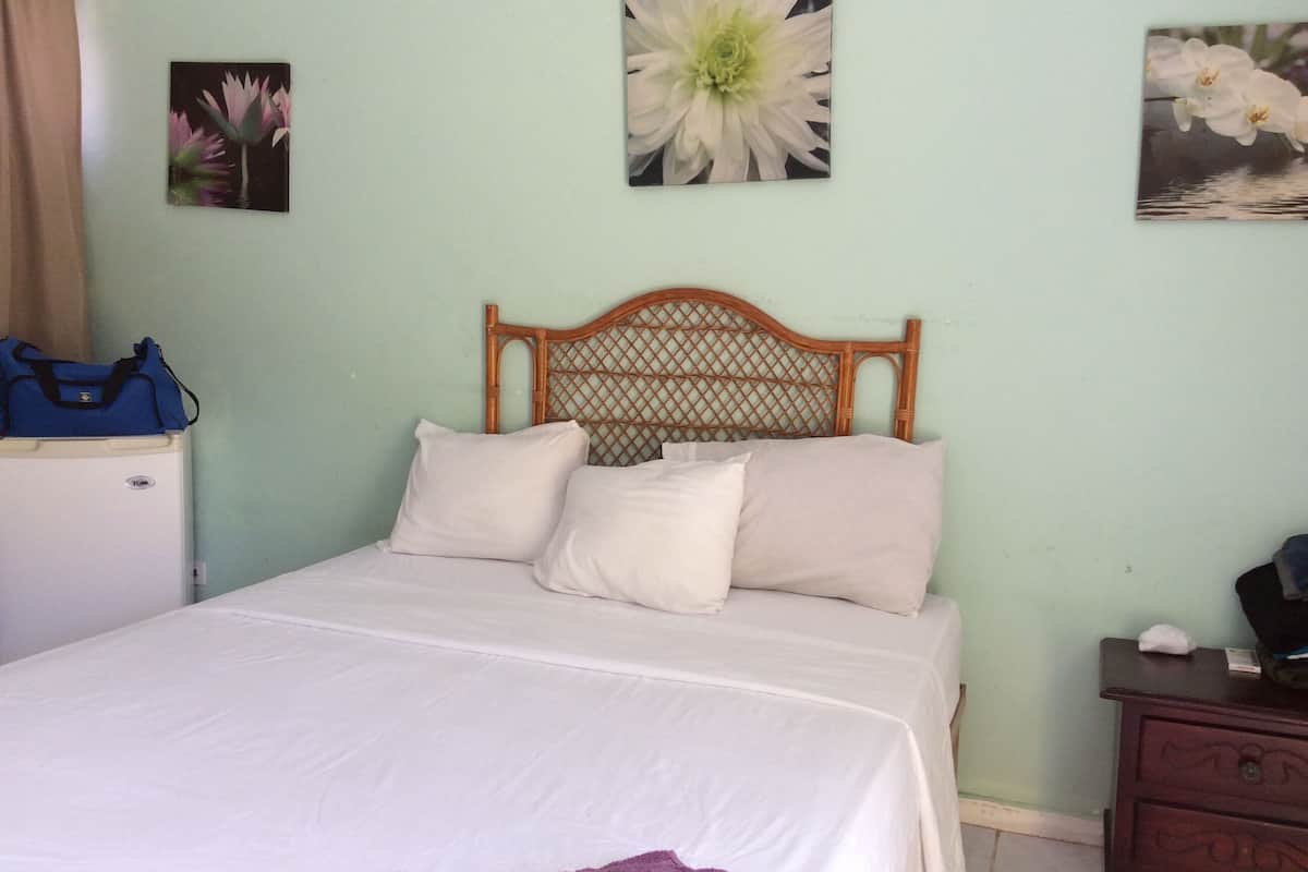 Un dormitorio con cama, cabecera de madera, mesita de noche y cómoda.