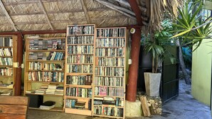 Un petit espace extérieur abrité, doté d’un toit de chaume et entouré d’étagères remplies de livres et de DVD.