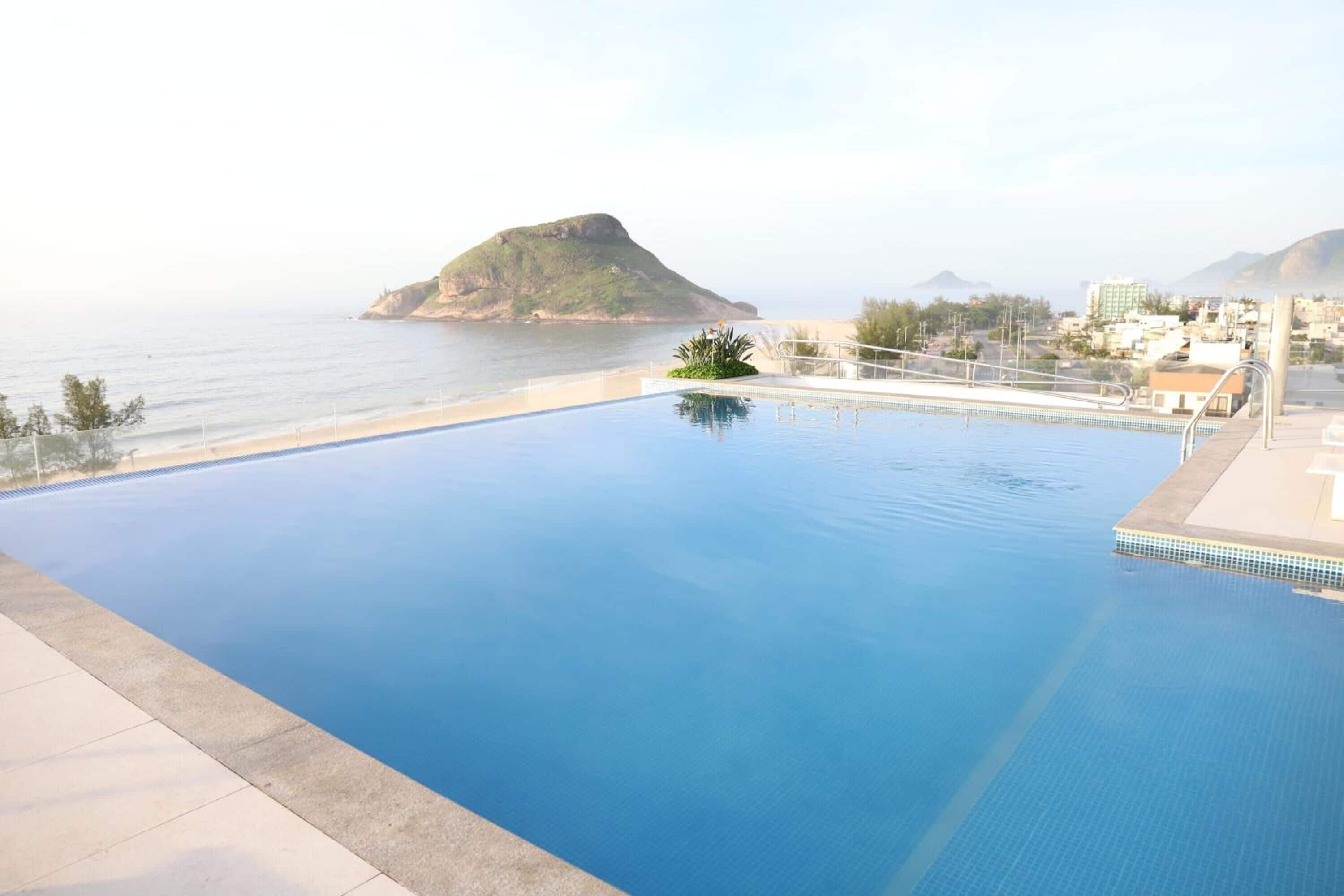 Ein Schwimmbecken mit Blick auf das Meer und eine kleine Insel.