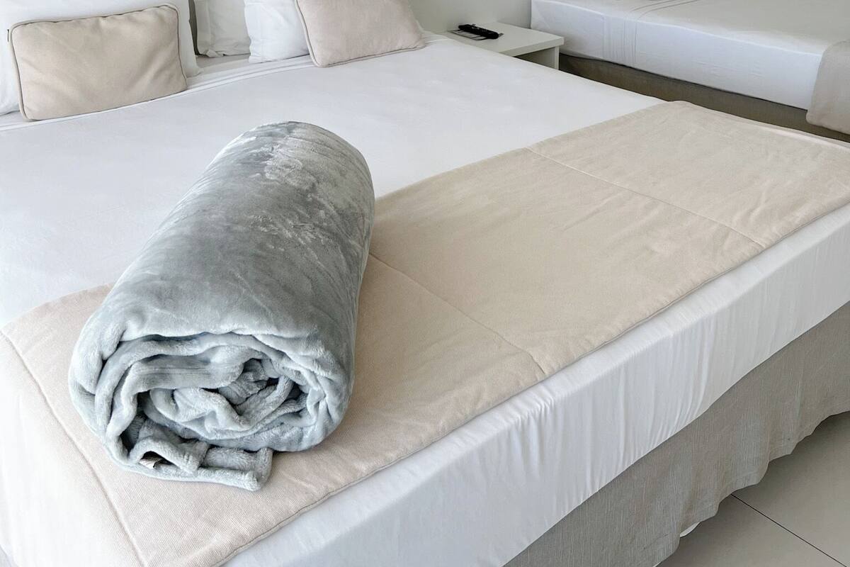 Una habitación de hotel con dos camas, una mesita de noche y otro apoyo para objetos nocturnos.