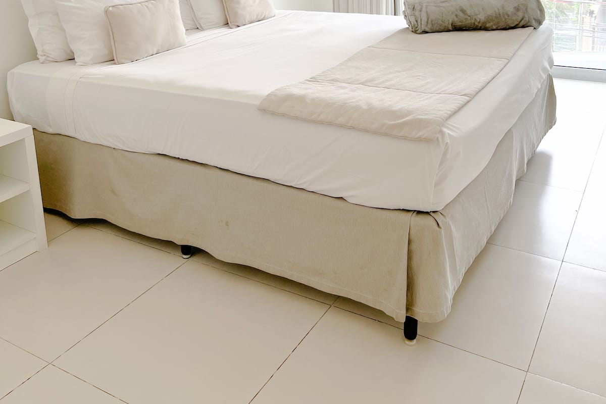 Un dormitorio moderno con una cama grande, ropa de cama blanca y vistas a un edificio a través de un ventanal.