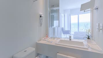 Un baño moderno con un espejo grande, un lavamanos blanco y un inodoro.
