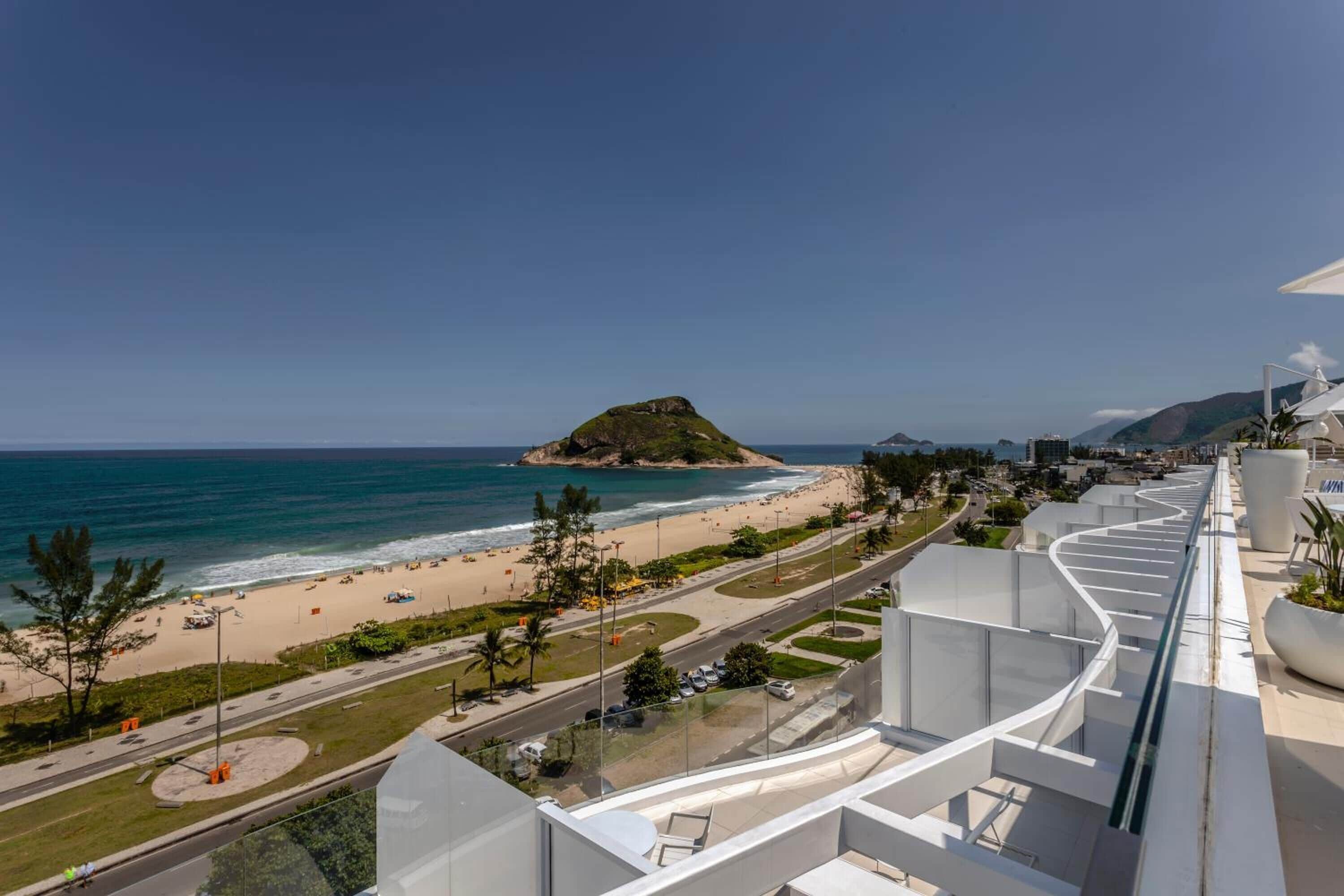 Um hotel moderno com varanda curva com vista para a praia e oceano.