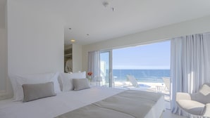 A hotel room with a large bed, a chair, and a balcony with a view of the ocean. - CDesign Hotel (Rio de Janeiro)