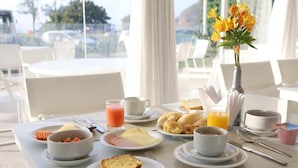 A breakfast table set with plates of food, including toast, eggs, and fruit, along with cups of coffee and juice. - CDesign Hotel (Rio de Janeiro)
