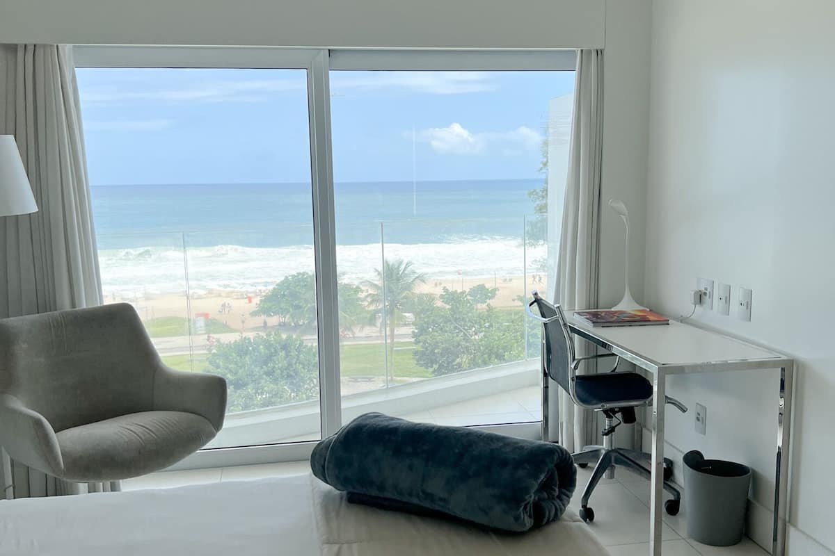 Una habitación de hotel con una cama, un escritorio, una silla y vistas a la playa.