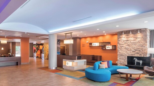 A modern lobby with a reception desk, seating area, and a stone wall with a fireplace. - Fairfield Inn & Suites by Marriott Houston Pasadena (Pasadena)