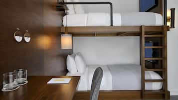 A bunk bed room with a wooden desk, two bedside tables, and a wall-mounted TV.