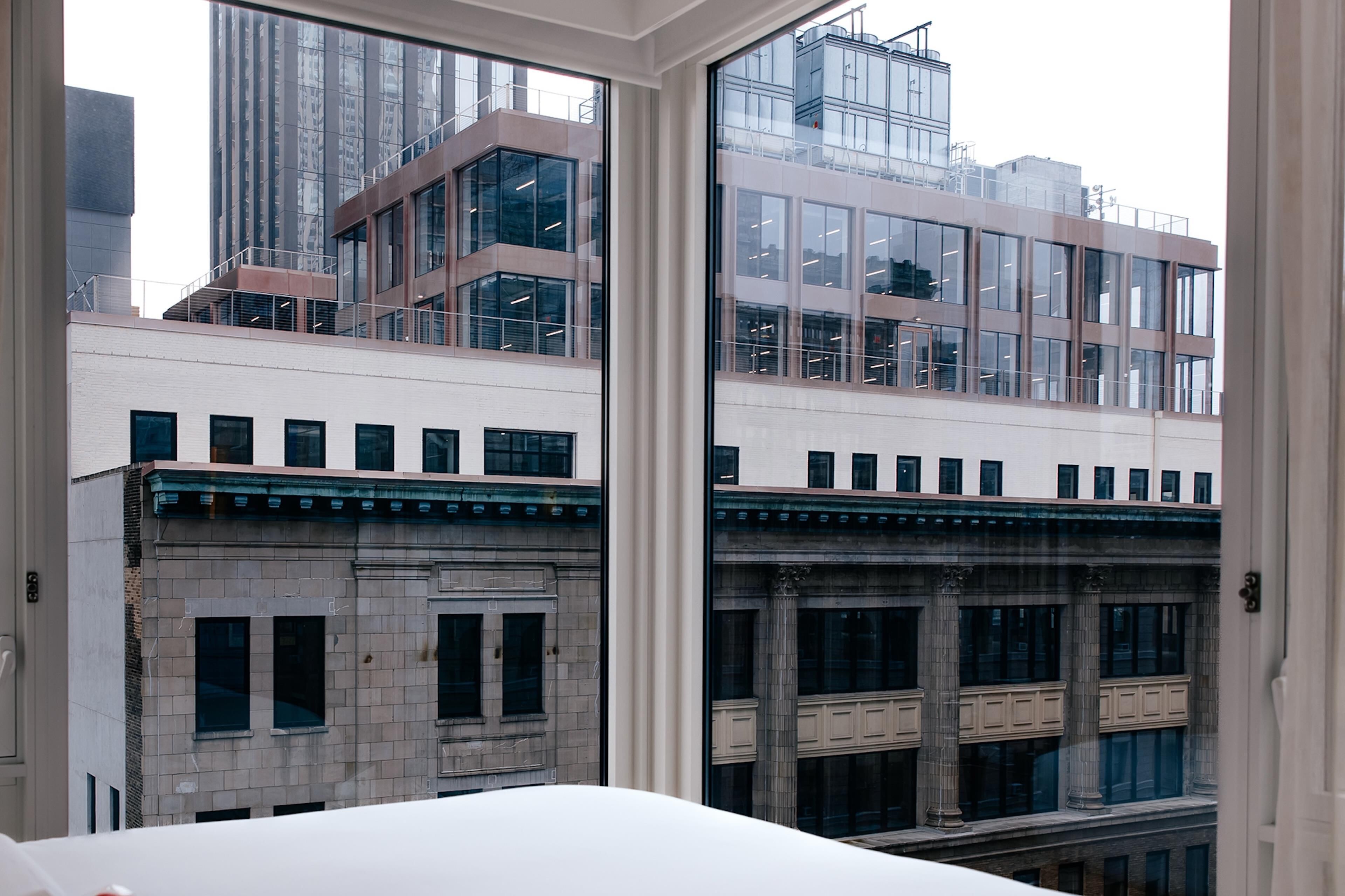A view through a window of a building with a white facade, large windows, and a balcony.