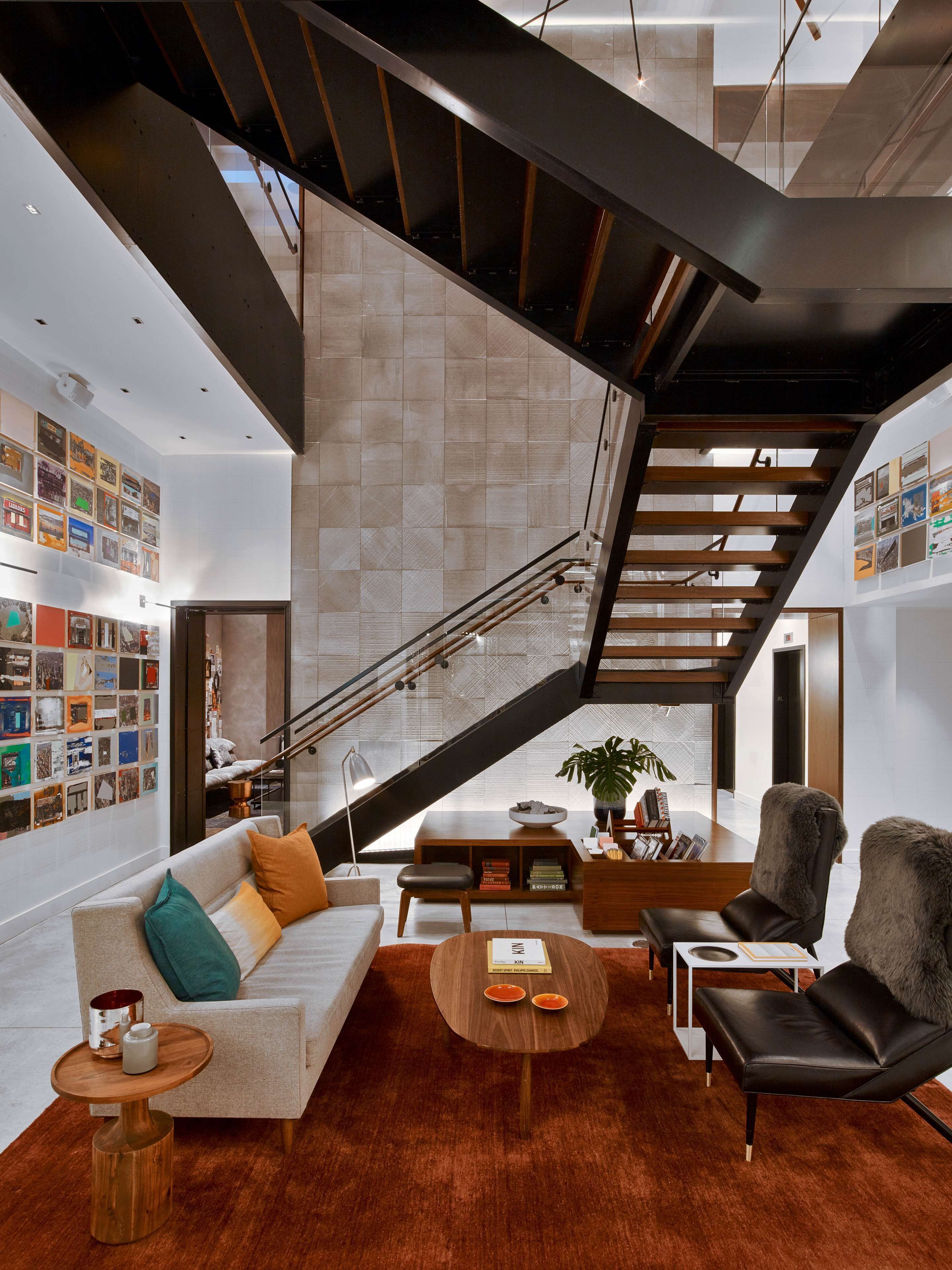 Ein modernes Wohnzimmer mit Treppe, Sofa, Couchtisch und Bücherregal.