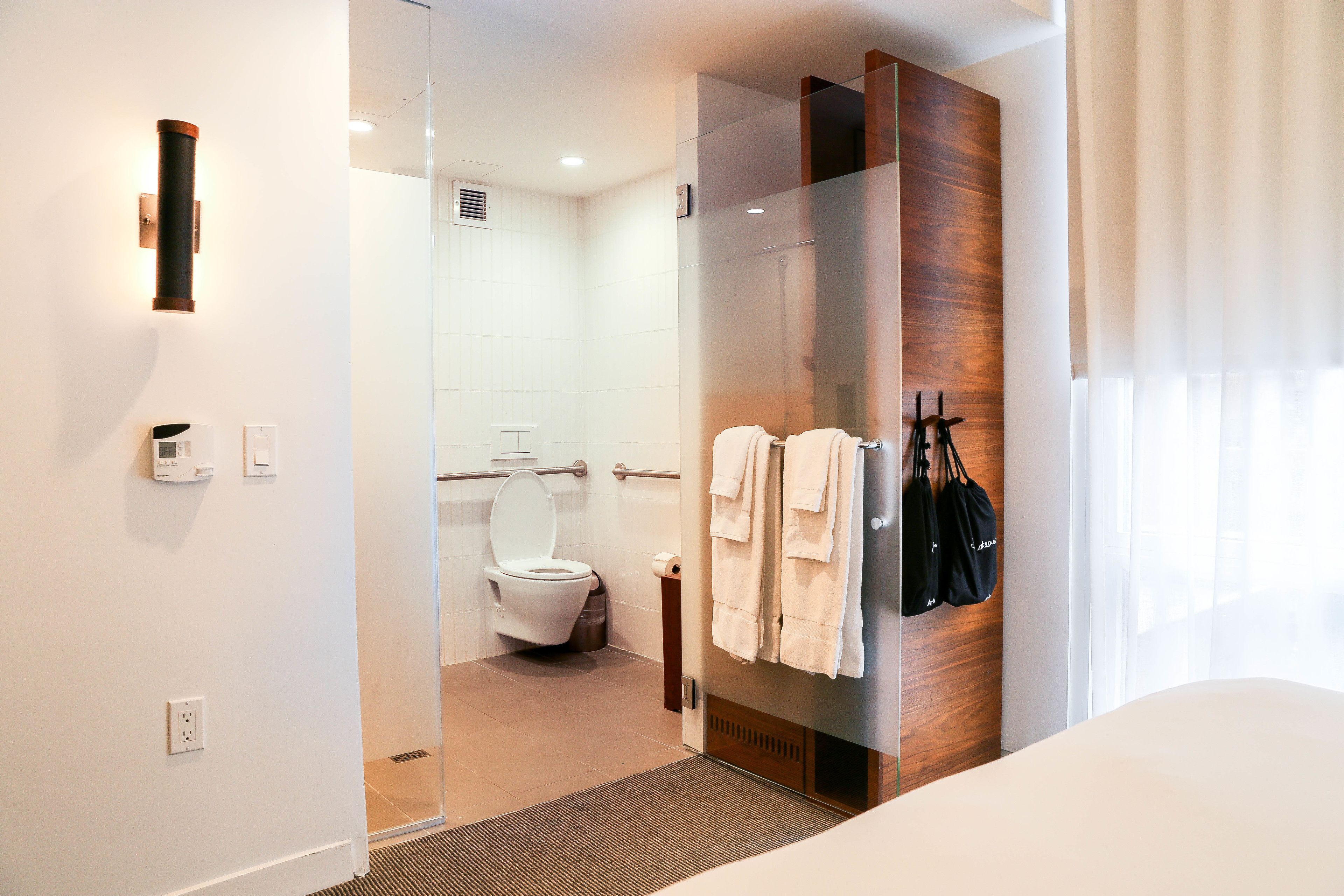 A modern bathroom with a glass shower enclosure, a toilet, and a towel rack with towels.
