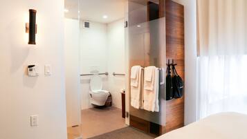 Une salle de bain moderne avec une douche à parois de verre, des toilettes et un porte-serviettes avec des serviettes.