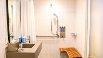Un baño moderno con ducha, lavabo, espejo y un banco de madera.