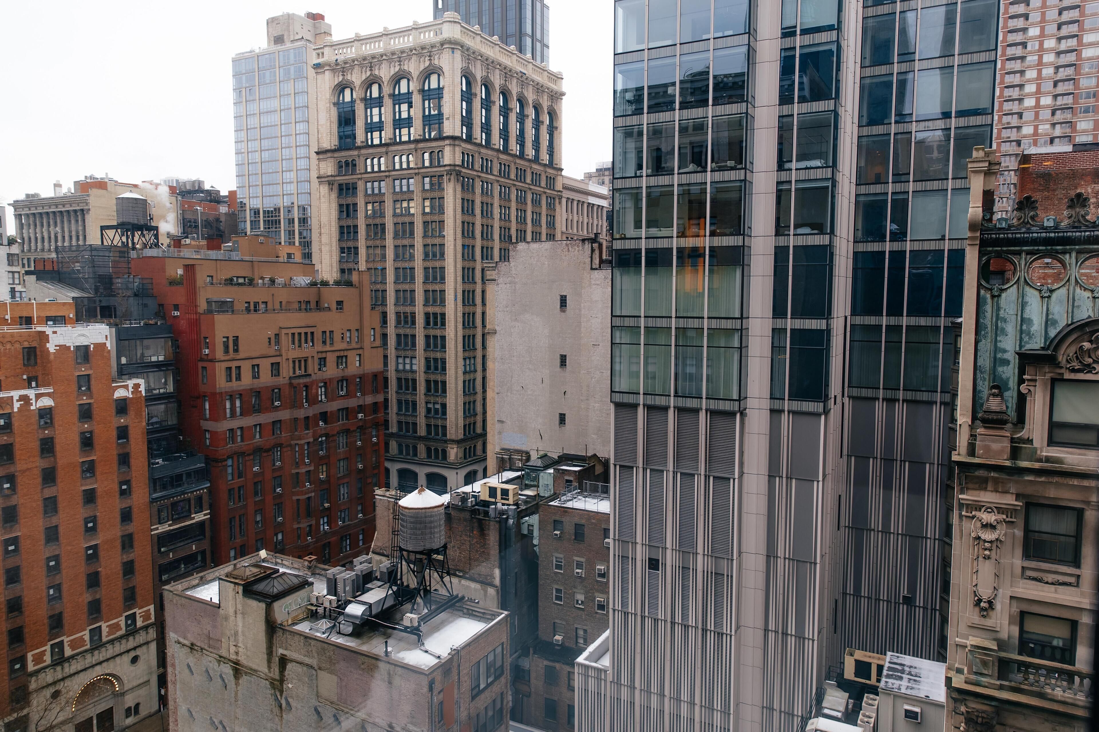 A high-rise building with a modern glass facade, surrounded by older brick buildings.