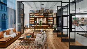 Ein stilvolles Wohnzimmer mit einer großen Bücherwand, Ledersofas und einem Essbereich.