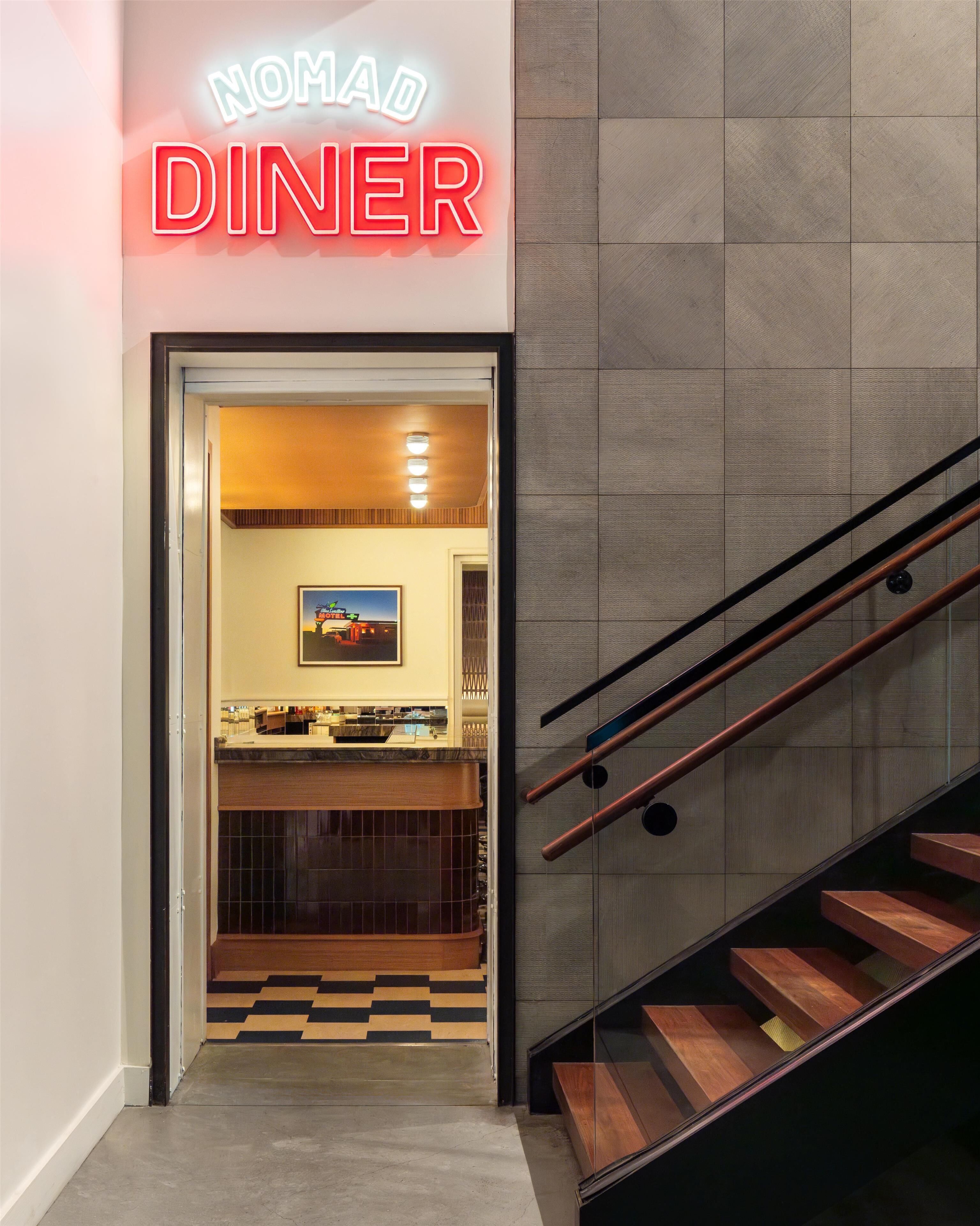 Entrada a NOMAD DINER con una escalera que lleva al interior.