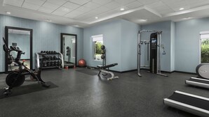 Un gimnasio moderno con equipamiento de ejercicio, un soporte para pesas y un espejo grande.