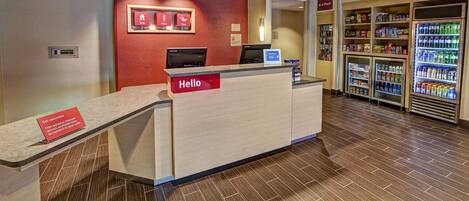 A hotel reception area with a reception desk, a digital display, and a vending machine.