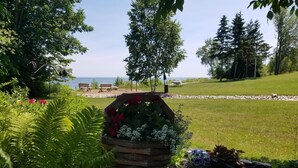 A garden with a wooden planter filled with flowers, a stone sculpture, and a white vase. - Square Rigger Harbor Motel (Baileys Harbor)