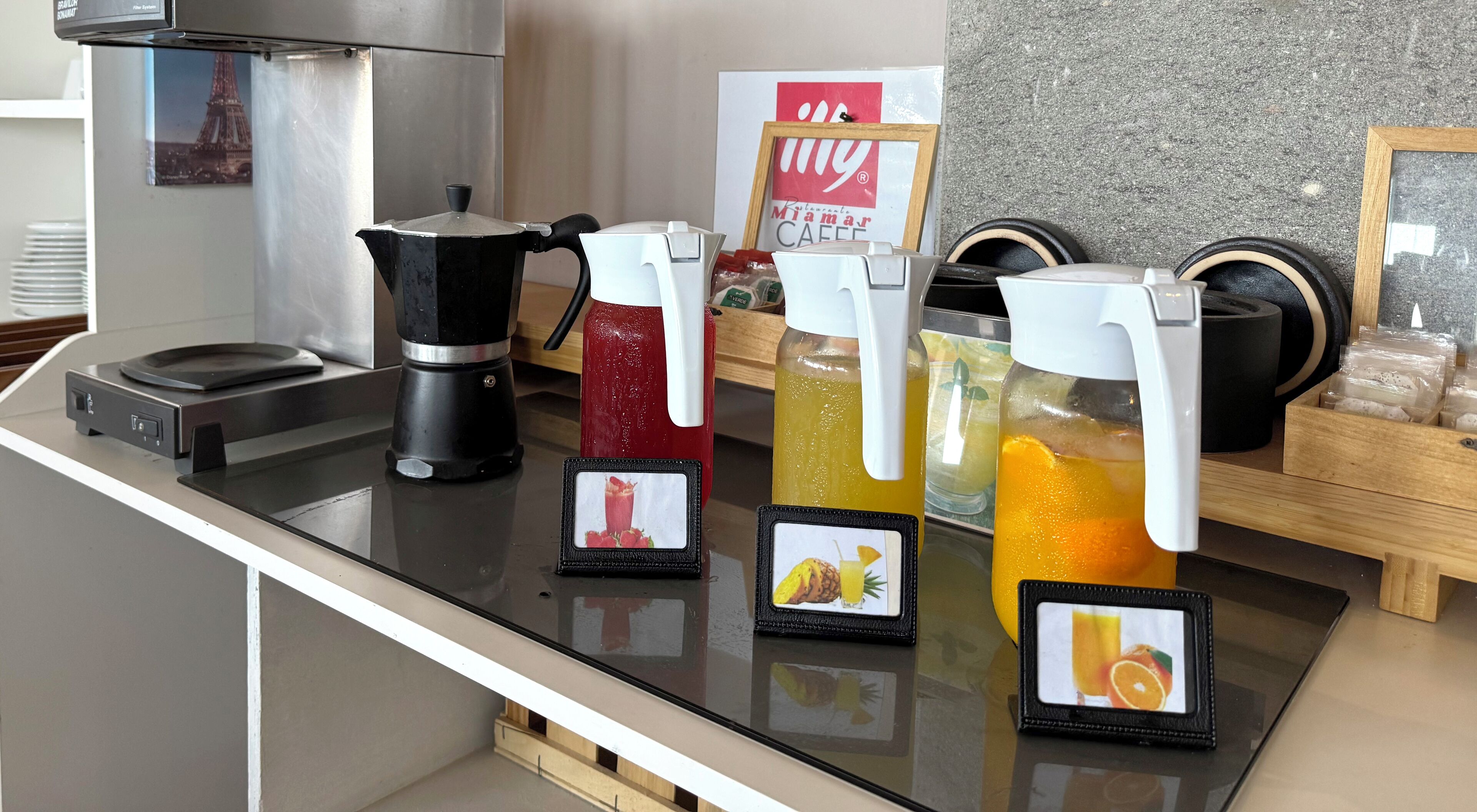 Un espace dédié au café, comprenant une machine à café, un distributeur de boissons rouges et deux distributeurs de jus d’orange.