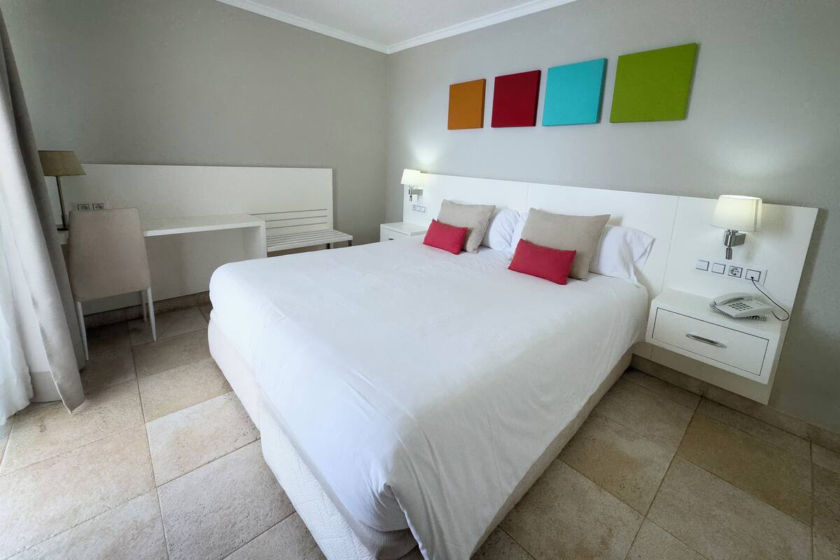 Een hotelkamer met een groot bed, nachtkastjes, een bureau en een stoel.