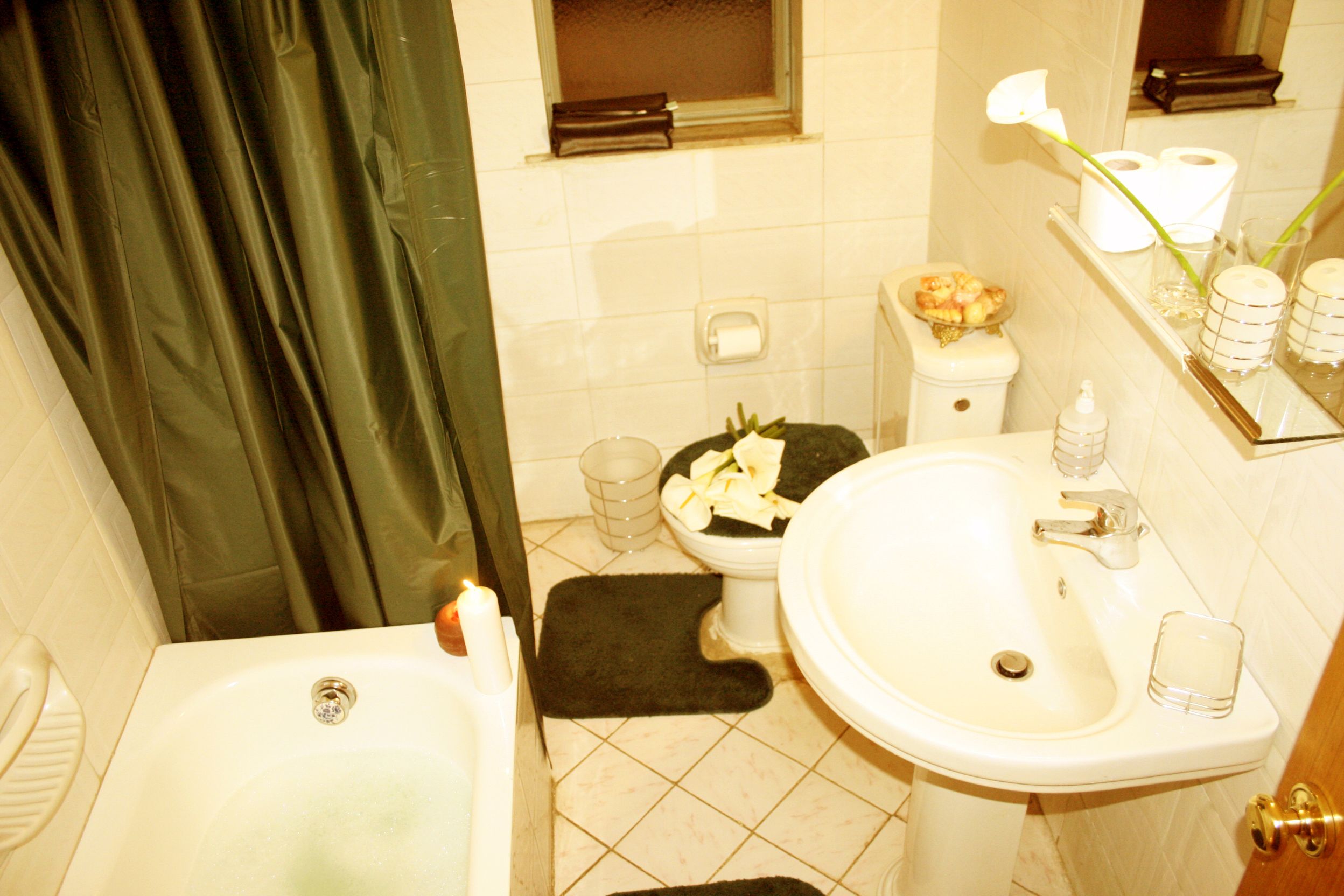 A bathroom with a bathtub, toilet, sink, and a small window.