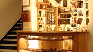 A lobby with a staircase, a glass display case with various items, and a mural on the wall. - Sunshine Hotel (Asmara)