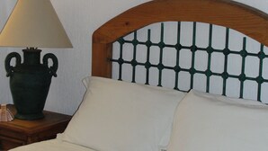 Una cama con cabecera de madera, una lámpara de noche y un adorno de pared.